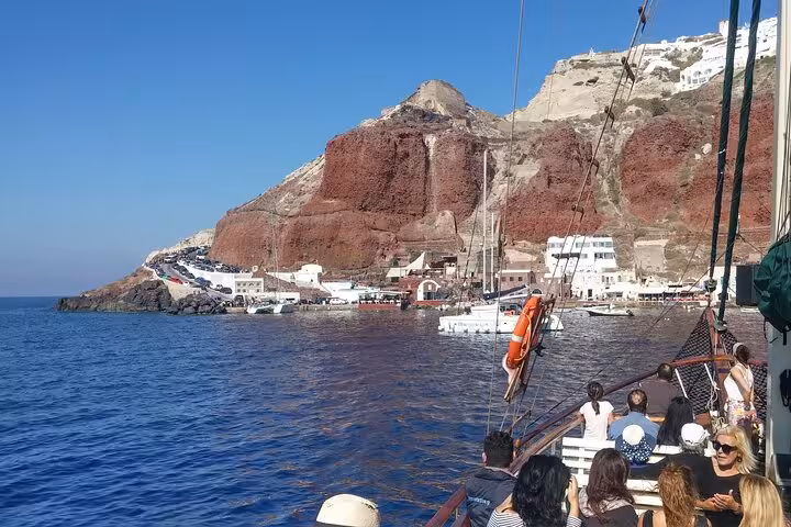 Boat view of Santorini red cliffs and harbor, ideal stop on Oia highlights shore excursion for cruise guests