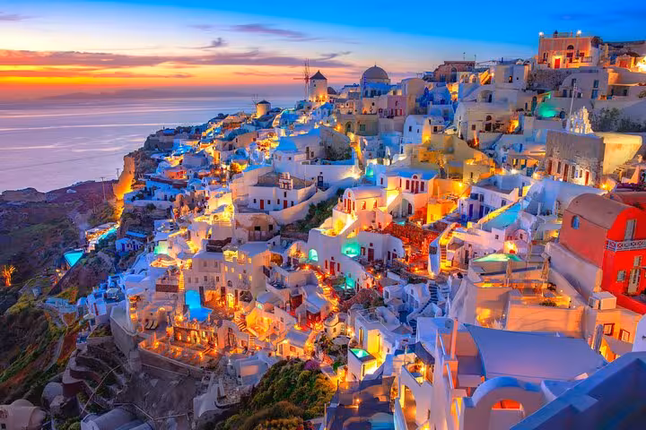 Sunset over Oia village, Santorini, with glowing whitewashed houses on a small group tour