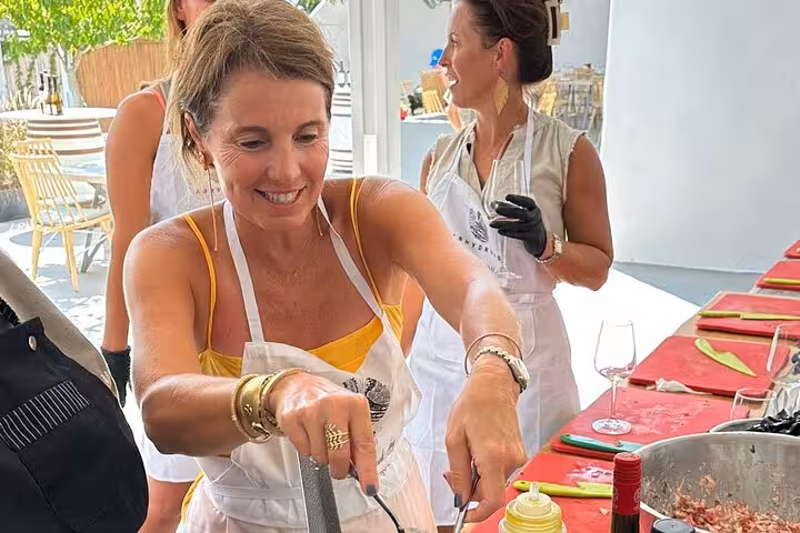 Guests prepare Greek meze at a Santorini private cooking class, hands-on lesson with local chef and island tour