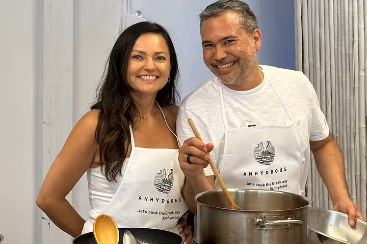 Guests stir a pot in a Santorini private cooking class, part of an island tour food and wine experience