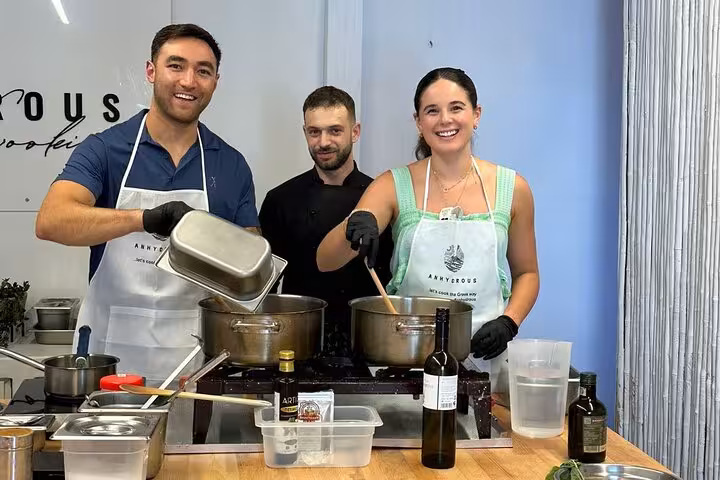 Guests cooking with local chef in Santorini private cooking class, hands-on Greek recipes and island tour experience