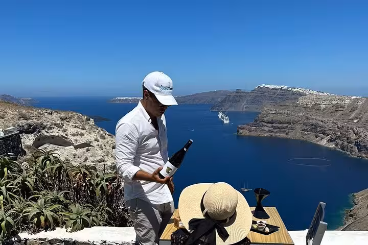 Private Santorini caldera wine tasting setup with bottle and glasses, part of 2–4 winery tour with snacks