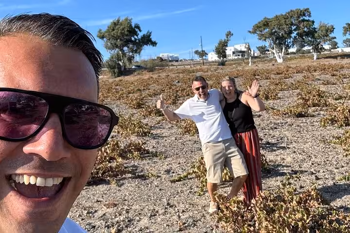 Guests posing in Santorini vineyard on private wine tasting tour with Wine Museum visit and local snacks