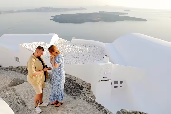 Santorini caldera proposal captured by personal photographer, couple on white cliffs at sunset in Oia