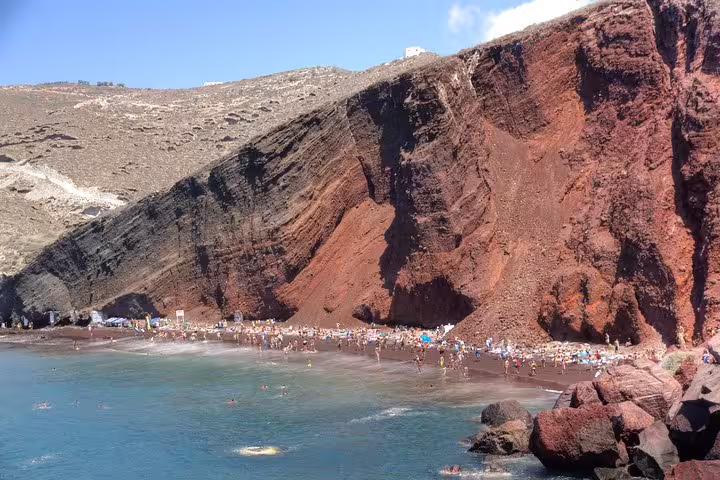 Red Beach in Santorini with dramatic volcanic cliffs and swimmers, featured on a 3-day private tour from Athens