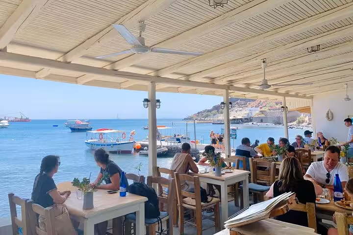 Seaside taverna lunch stop on Santorini 8-hour Island of Thera tour, with boats and Aegean harbor views