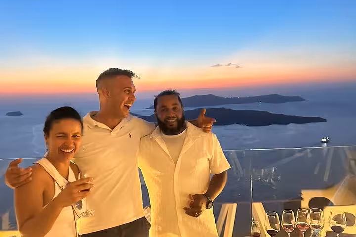 Friends toast Santorini sunset with local wine tasting, caldera views, two wineries and tapas experience