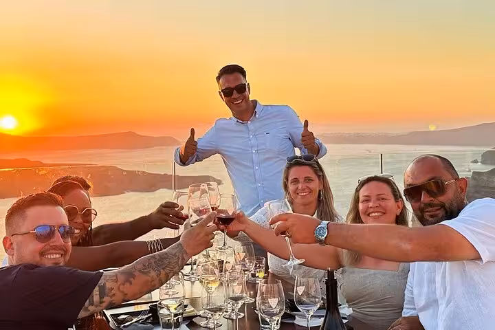 Friends toast Santorini wines at sunset with caldera views during the best views 2 wineries and tapas experience