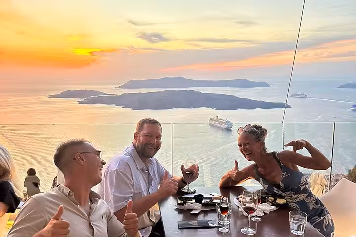 Friends enjoy Santorini sunset caldera views with wine tasting and tapas on a best views two-winery tour