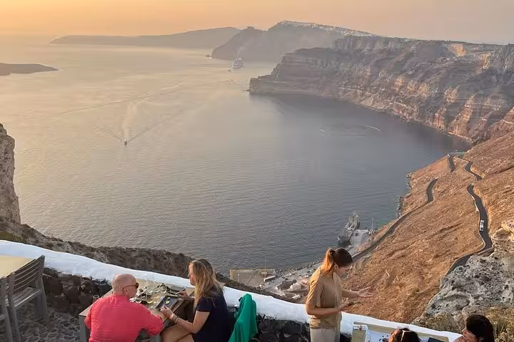 Santorini caldera sunset view with guests enjoying wine and tapas tasting on scenic winery terrace