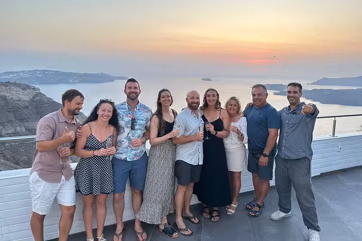 Guests toast at sunset viewpoint on private Santorini wine tour, visiting 3 wineries with tapas pairing