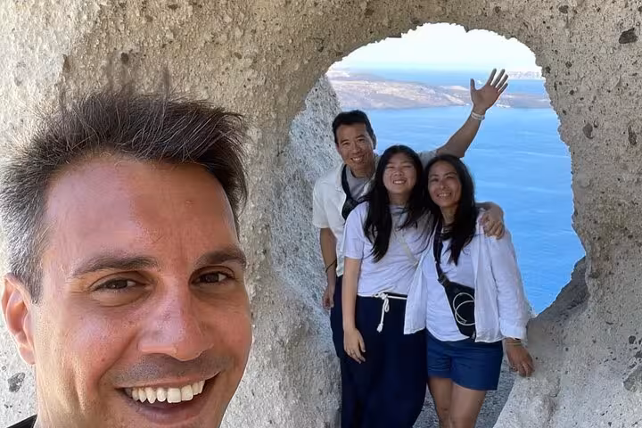 Happy guests at Santorini caldera viewpoint during Island of Thera one-day tour with lunch and wine tasting
