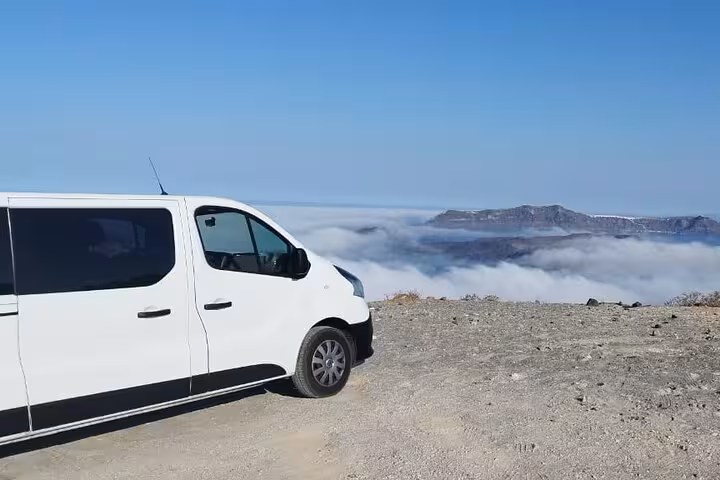 Tour van at Santorini caldera viewpoint above the clouds, scenic stop on One Day Escape to Enchanting Santorini
