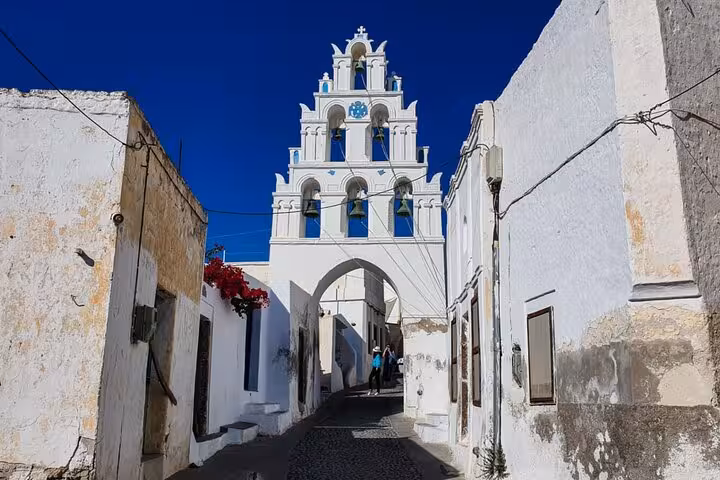 White bell tower and cobblestone lane in Santorini village on a private day tour from Crete with transfers