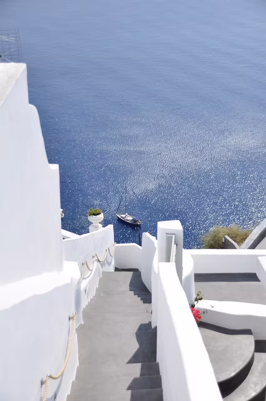 Santorini whitewashed stairway descending to the caldera, sparkling Aegean view on iconic highlight tour