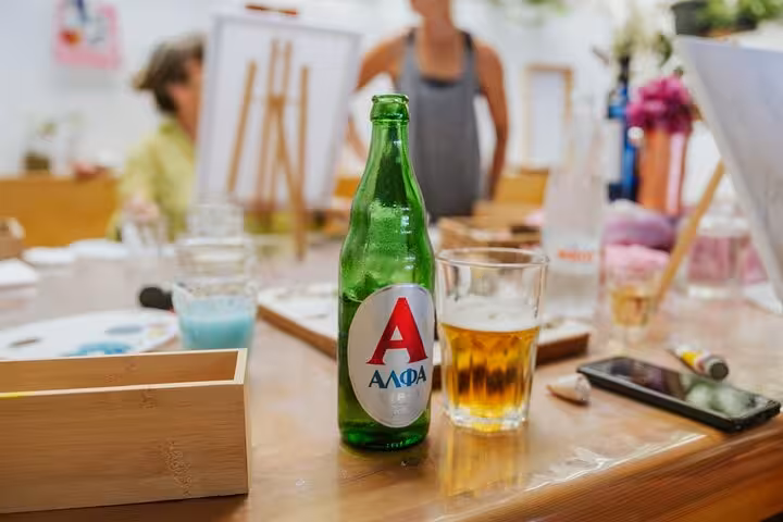 Greek beer and art supplies on a studio table during Santorini Wine and Paint class with local tasting