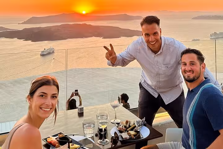 Guests enjoy Santorini wine and paint tour at sunset, dining with caldera views in Oia, Greece