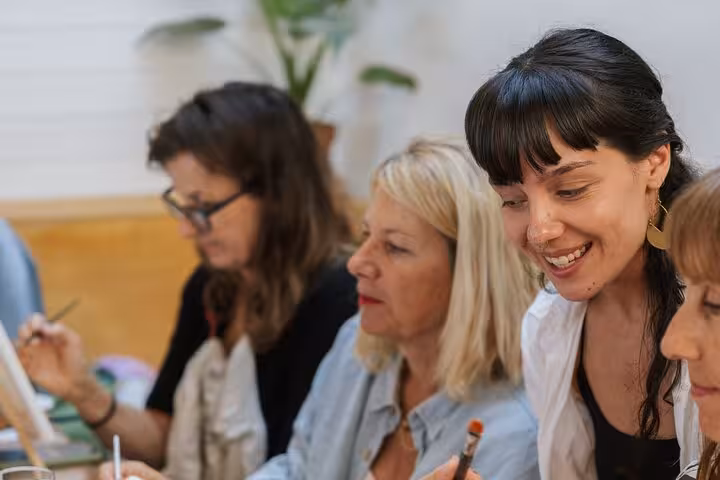 Participants smile during Santorini wine and paint workshop, guided art class with local Greek wine tasting