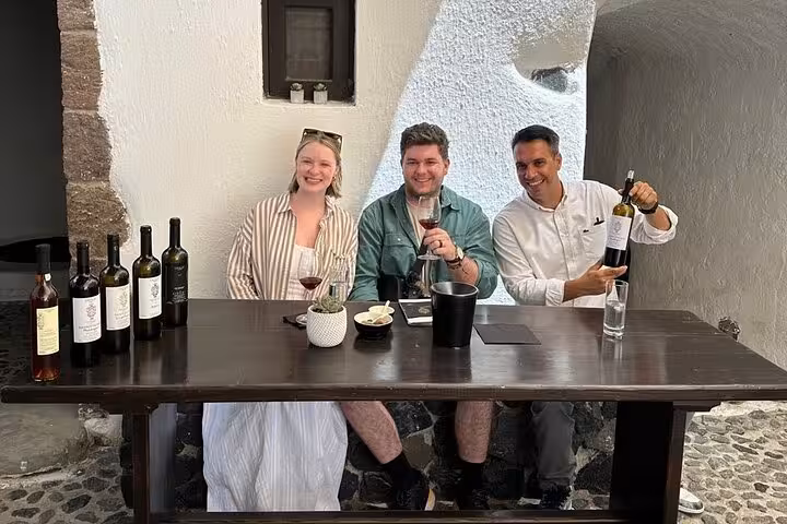 Happy group wine tasting in Santorini cave winery, part of Santorini premier wine and paint adventure tour