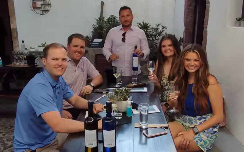 Private Santorini wine tasting tour group sampling Assyrtiko at a winery table with sommelier