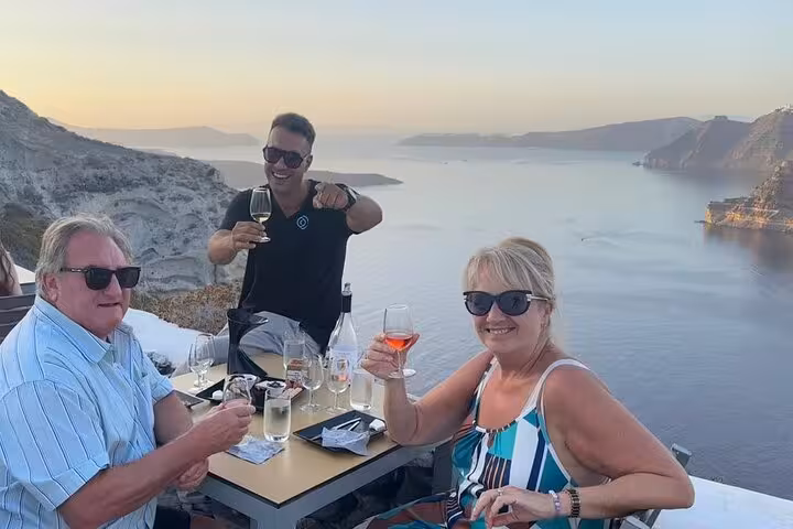 Guests sipping Santorini wine at sunset with caldera views on a private tour winery tasting terrace