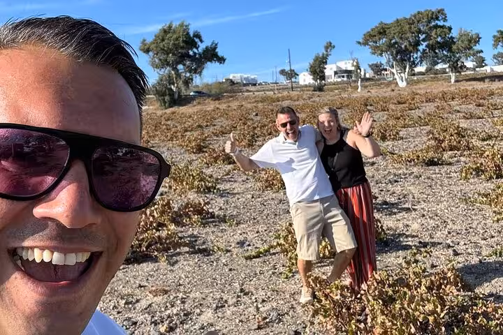Guests posing in Santorini vineyards on a private wine tour, exploring top wineries and volcanic terroir