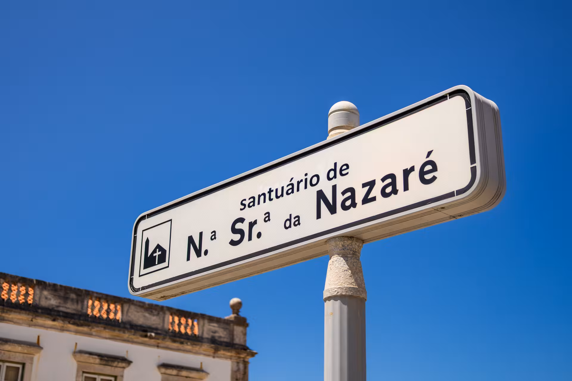 Sign for Santuário de Nossa Senhora da Nazaré against a clear blue sky on Lisbon to Nazaré tour.