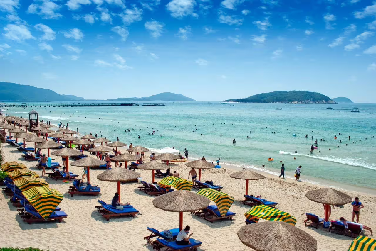 Relax on Sanya's picturesque beach with sun loungers and umbrellas, perfect for a cultural city break tour.