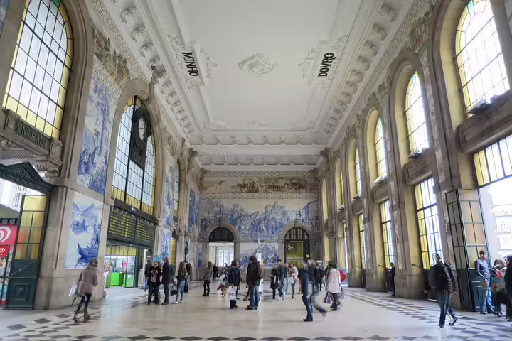 Inside São Bento Railway Station in Porto, showcasing iconic azulejos murals and bustling tourists, perfect for cultural tours.