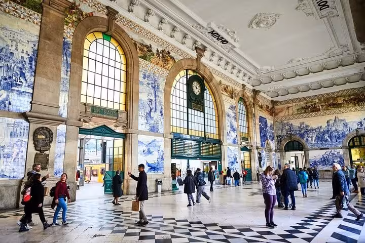 Interior of São Bento Station in Porto, showcasing iconic azulejo tiles and bustling travelers.