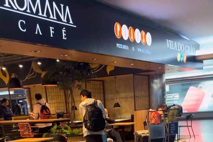 Travelers at Romana Café in São Paulo airport, ideal stop before a Paraty shuttle journey, enjoying a relaxed atmosphere.