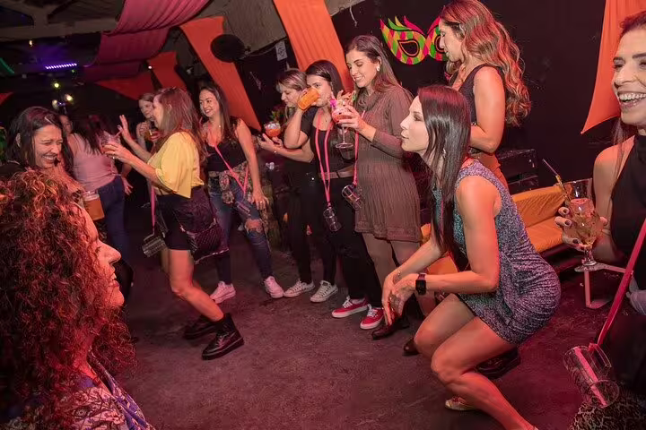 Excited crowd enjoying drinks and dancing at a bustling São Paulo nightclub during an unforgettable pub crawl.