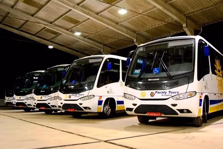 Fleet of Paraty Tours shuttle buses parked under a shelter, ready for transfers from São Paulo to Paraty.