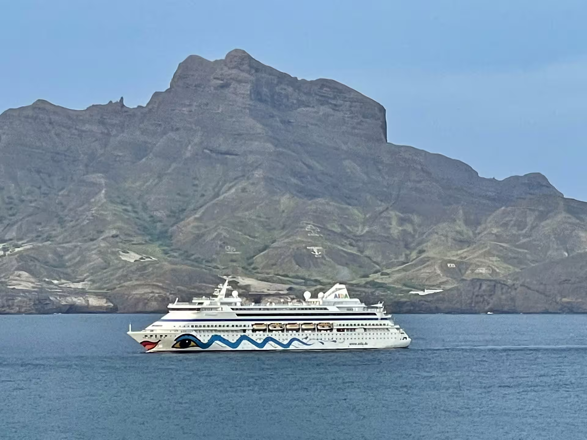 Cruise ship sailing near the dramatic volcanic landscape of São Vicente, Mindelo, ideal for full-day shore excursions.