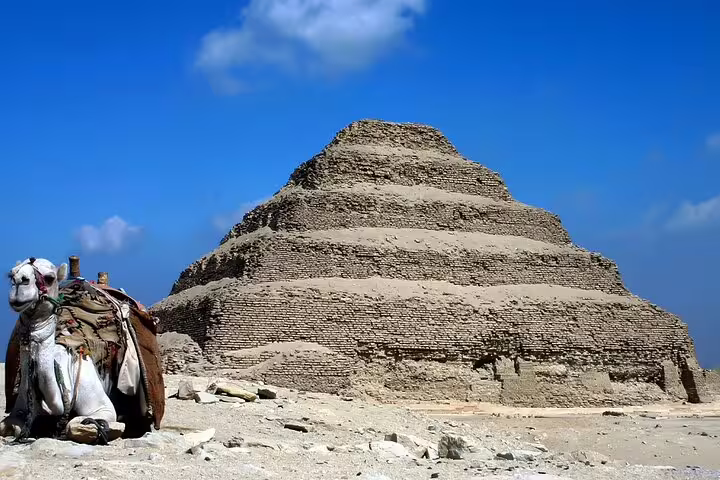 Saqqara Step Pyramid with resting camel under blue sky, Cairo layover tour to pyramids and Dahshur