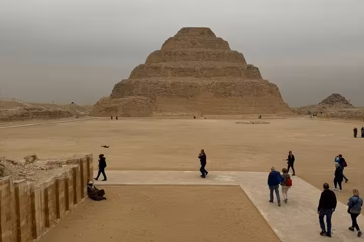 Tourists walking toward Saqqara Step Pyramid on a private day tour from Cairo to Giza Pyramids, Sphinx and Memphis