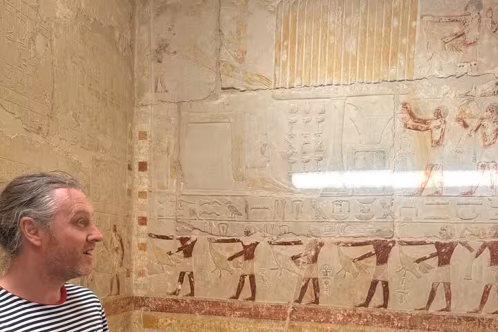 Visitor admiring ancient wall reliefs inside Saqqara tomb on private Saqqara Memphis and Dahshur tour from Cairo