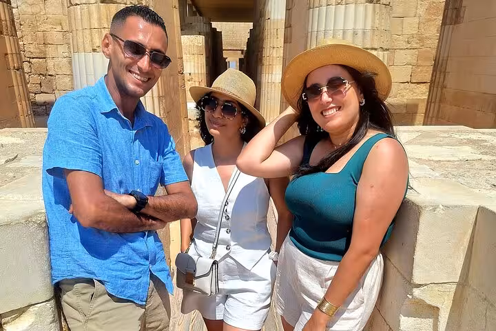 Smiling visitors at the ancient Saqqara site, showcasing Egyptian architecture and sunny weather.