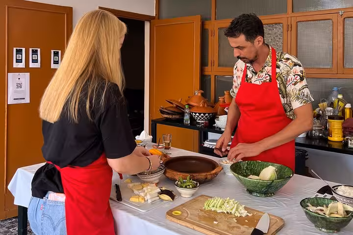 Instructor guiding a participant in Sardin Tawa Cooking Class Marrakesh, showcasing a variety of fresh ingredients.
