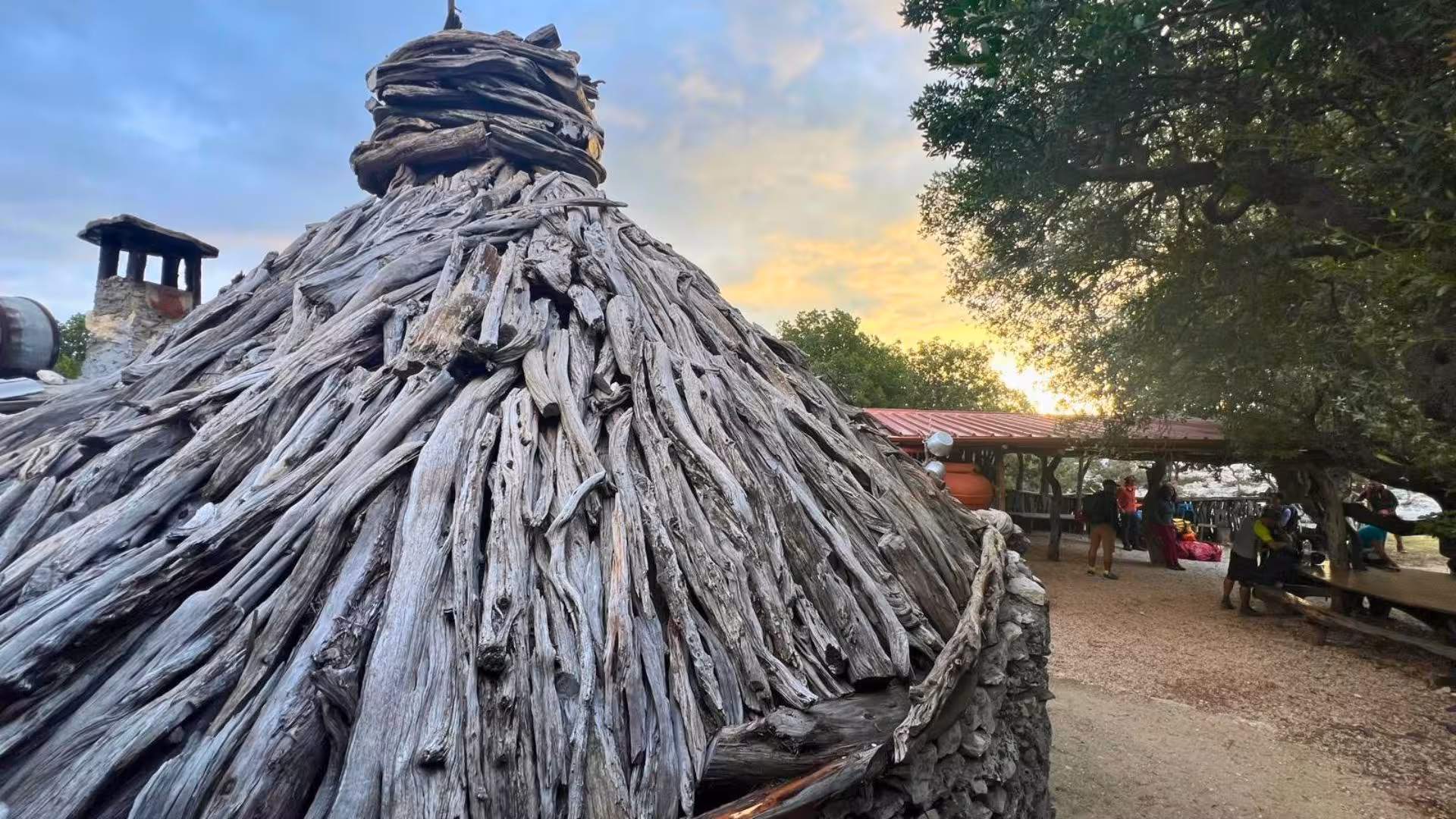 Traditional Sardinian hut made of driftwood at sunset, capturing the rustic charm of the Selvaggio Blu trek campsite.
