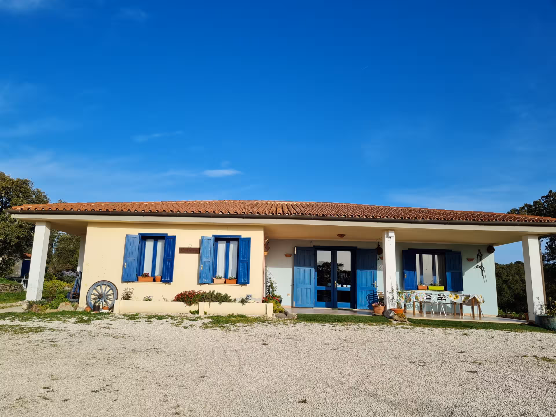 Charming Sardinian farmhouse with blue shutters under a clear sky, perfect for a shepherd's lunch in Bitti.