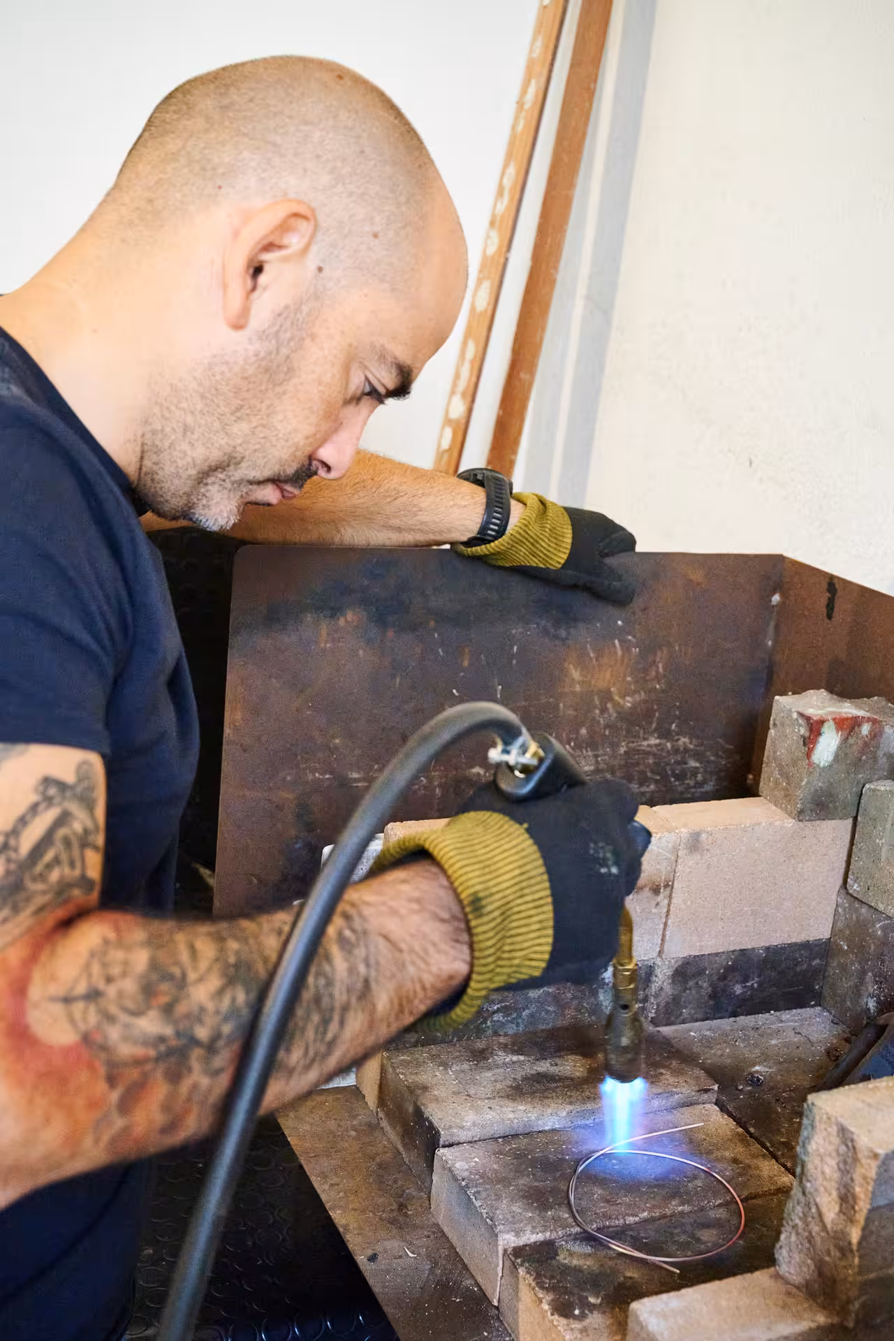 Artisan in Dorgali expertly using a blowtorch to shape metal wire for Sardinian filigree jewelry.