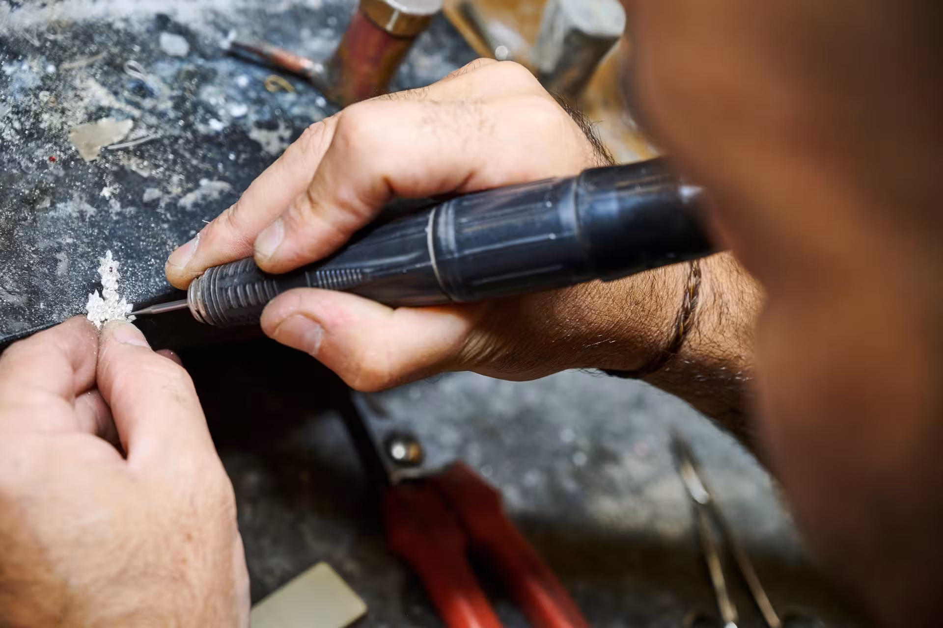 Close-up of a craftsman intricately working on Sardinian filigree jewelry in Dorgali's goldsmith lab.