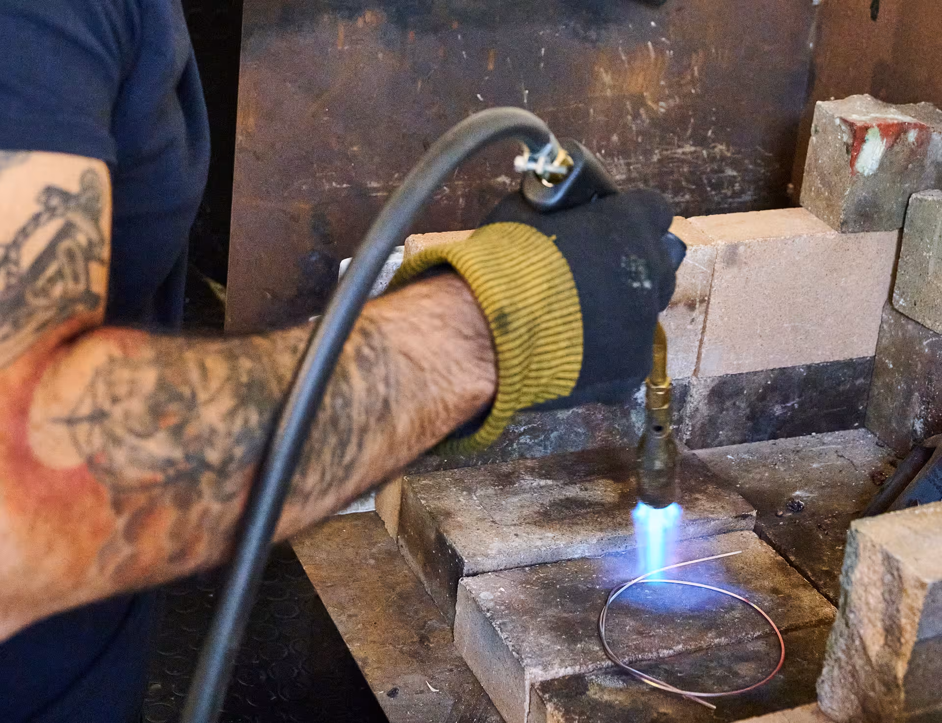Craftsman heating metal wire with a torch in Dorgali's Sardinian filigree jewelry workshop.