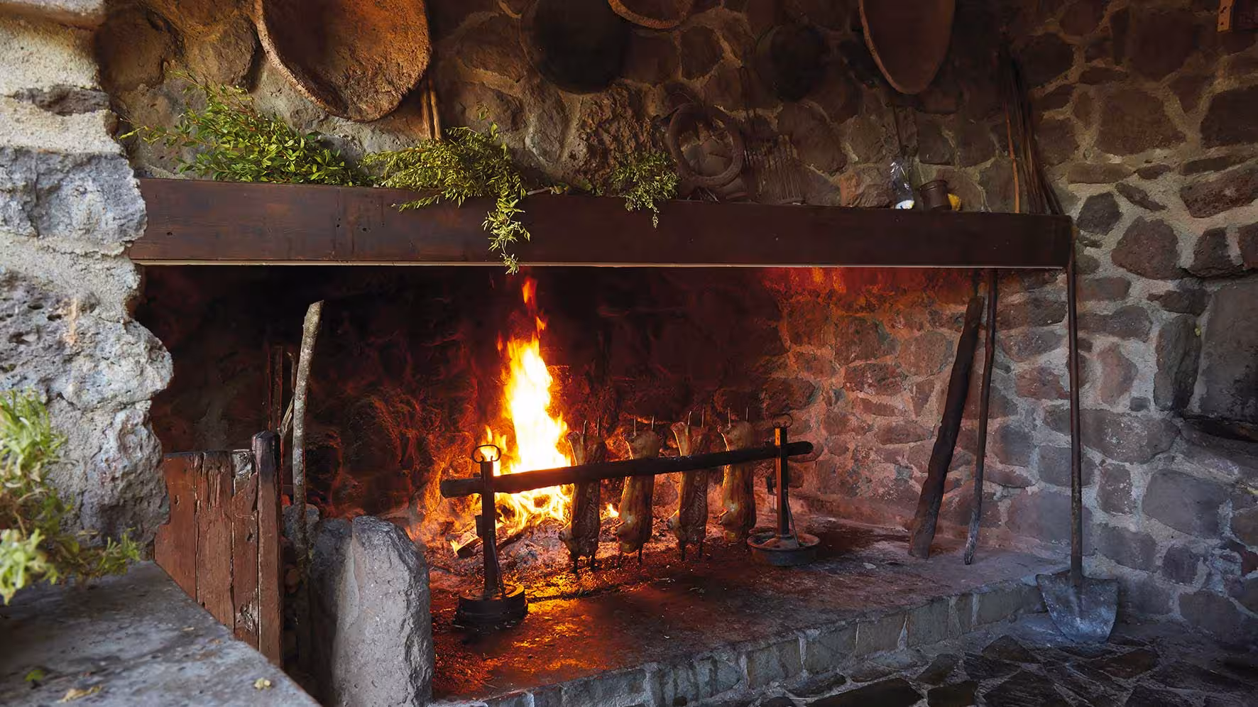 Traditional Sardinian fireplace with roasting meat, showcasing Dorgali's authentic culinary experience.