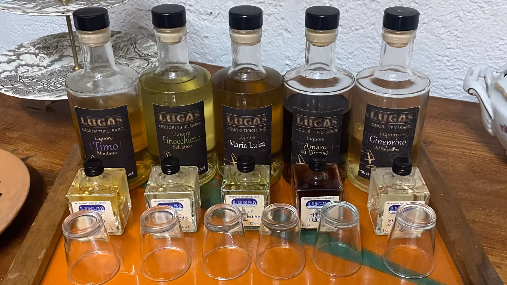 Assortment of Sardinian liqueurs displayed for Laconi tour, featuring bottles and tasting glasses on a rustic tray.