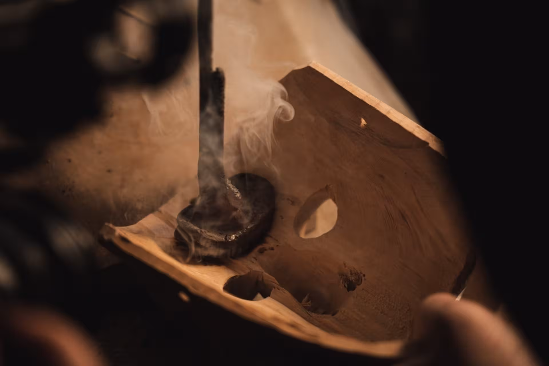 Close-up of wood burning process on a traditional Sardinian mask in Mamoiada workshop.