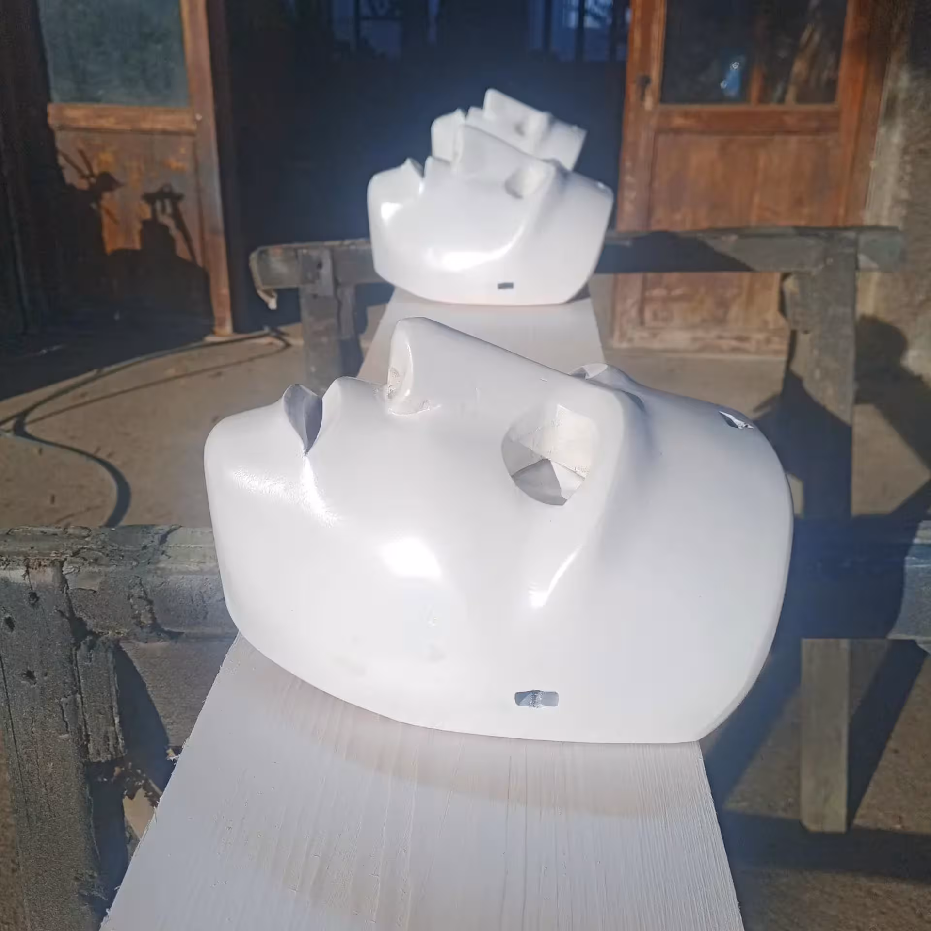 Row of white Sardinian masks drying in sunlight at Mamoiada workshop.