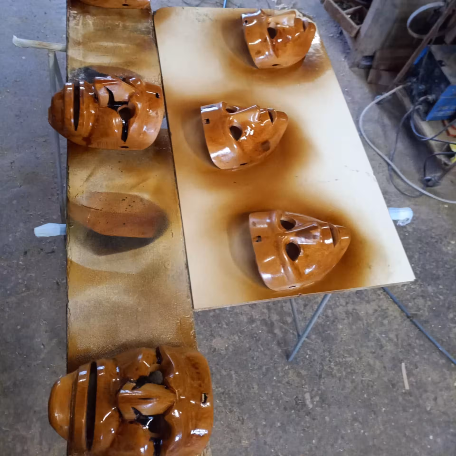 Freshly painted Sardinian masks drying on a table in Mamoiada's renowned mask workshop.