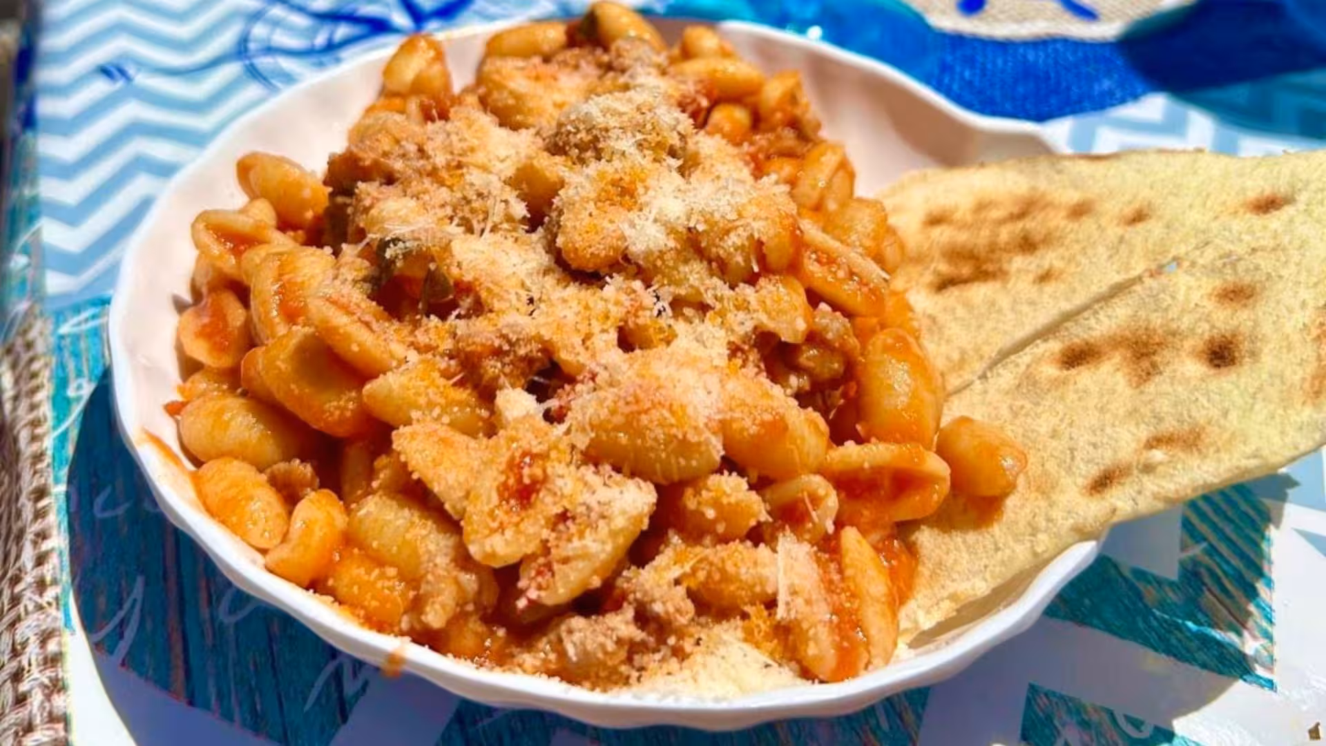 Delicious Sardinian pasta dish with grated cheese and flatbread, enjoyed on a sailing trip in La Maddalena archipelago.